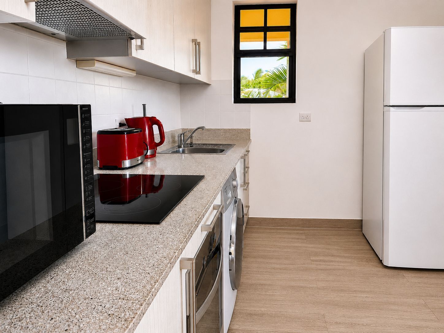 A modern kitchen with a microwave, red coffee maker, and a white refrigerator.