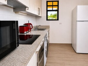 Eine moderne Küche mit Mikrowelle, rotem Kaffeeautomaten und einem weißen Kühlschrank.