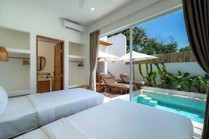 Ein modernes Hotelzimmer mit einem großen Bett, einem separaten Schlafbereich, einem Badezimmer und einem privaten Poolbereich.