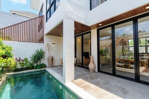 Ein modernes Haus mit Schwimmbad, großen Fenstern und einem Essbereich, der durch die Glastüren sichtbar ist.