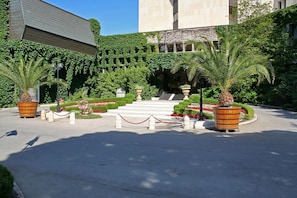 A courtyard with a central staircase, surrounded by greenery and potted plants. - Hotel Imperial - Riviera Holiday Club Varna (Varna)