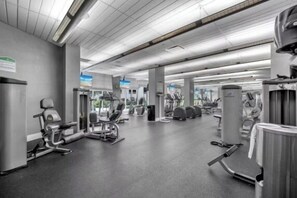 A gym with various exercise machines, a mirrored wall, and a ceiling with exposed beams. - Home w/2 Queen beds at Tides (Hollywood)