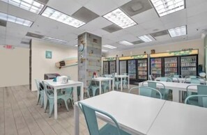 A cafeteria with tables and chairs, a refrigerator, and a wall-mounted clock. - Home w/2 Queen beds at Tides (Hollywood)