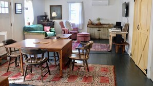 A cozy room with a wooden dining table, chairs, a sofa, a TV, and a cabinet. - Cute Modern Farmhouse in Essex, . (Essex)