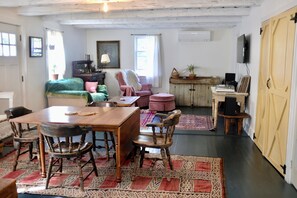 A cozy room with a wooden dining table, chairs, a sofa, a TV, and a cabinet.
