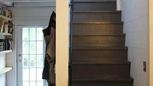 A staircase with a wooden handrail and a door at the top leading to an outdoor area. - Cute Modern Farmhouse in Essex, . (Essex)