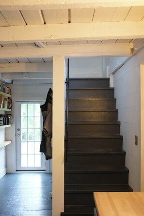 A staircase with a wooden handrail and a door at the top leading to an outdoor area.