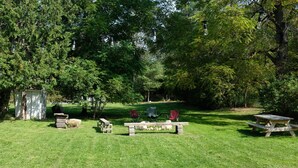 A picnic area with benches and chairs, surrounded by trees. - Cute Modern Farmhouse in Essex, . (Essex)