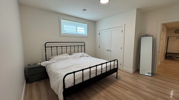 A bedroom with a bed, a nightstand, a wardrobe, a mirror, and a window.