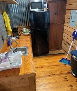 A compact kitchen with a microwave, refrigerator, sink, and wooden cabinets.