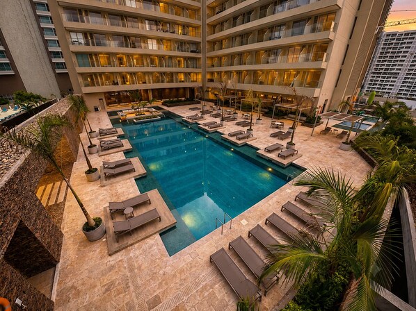 A hotel with a large indoor pool, multiple floors, and outdoor seating areas. - 16th floor with panoramic views of the ocean and sunsets (Santa Marta)