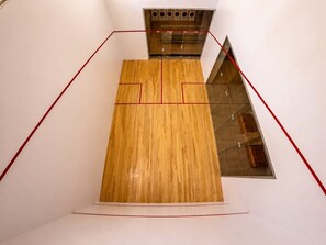 A squash court with wooden flooring and red boundary lines, surrounded by white walls. - 16th floor with panoramic views of the ocean and sunsets (Santa Marta)