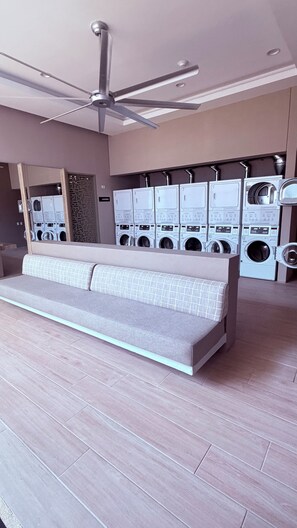 A modern laundry room with multiple washing machines, a ceiling fan, and a seating area. - 16th floor with panoramic views of the ocean and sunsets (Santa Marta)