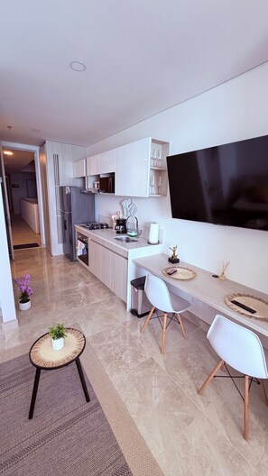 A modern kitchen with a TV, dining area with chairs, and a small table with a plant. - 16th floor with panoramic views of the ocean and sunsets (Santa Marta)