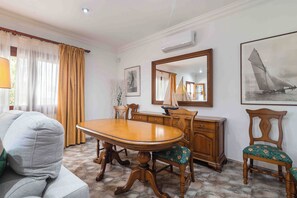 A dining area with a wooden table, chairs, a sofa, a dresser, and a sailboat painting. - Fantastic villa with pool in Puerto de Alcudia (Port d'Alcúdia)