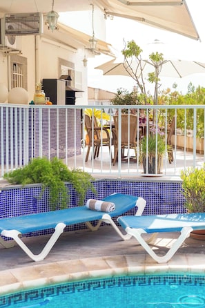 Ein Poolbereich mit Liegestühlen, einem gefliesten Pool und Gartenmöbeln.