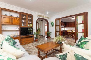 A living room with a television, wooden cabinets, a sofa, and a dining area with a table and chairs. - Fantastic villa with pool in Puerto de Alcudia (Port d'Alcúdia)