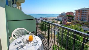Un balcón con mesa, sillas y vistas al mar y edificios.