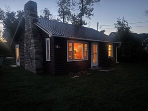 Uma cabana de toras com chaminé de pedra, número 862, e várias janelas iluminadas.