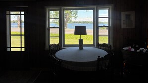Une pièce dotée d’une grande fenêtre donnant sur une étendue d’eau, d’une table ronde avec une lampe et d’une chaise.