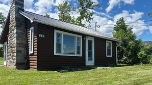 Une cabane en rondins d’un seul étage, dotée d’une cheminée en pierre et portant le numéro 862, avec une porte d’entrée, deux fenêtres et un petit porche.