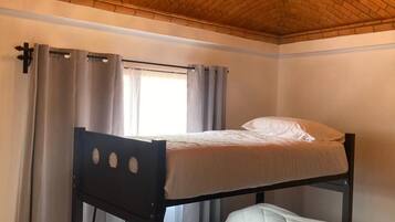 Een kamer met een stapelbed, een kroonluchter en een raam met gordijnen.