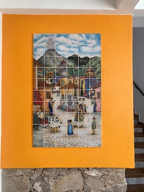 Un mural de azulejos con una escena de un pueblo, una pared de piedra y una escalera.