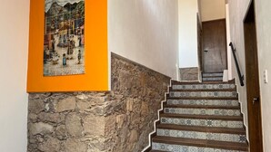 A staircase with patterned tiles, a stone wall, and a framed artwork on the wall.