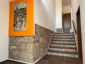 A staircase with patterned tiles, a stone wall, and a framed artwork on the wall.