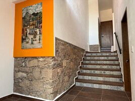 Una escalera con azulejos estampados, una pared de piedra y una obra de arte enmarcada en la pared.