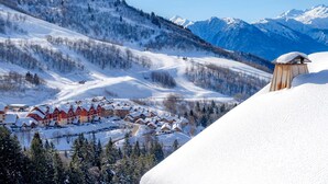 A snow-covered mountain landscape with a ski resort featuring chalet-style buildings.