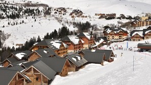 A snow-covered mountain resort with wooden cabins and a ski slope. - Goelia - Le Village Gaulois (Saint-François-Longchamp)