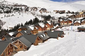 A snow-covered mountain resort with wooden cabins and a ski slope. - Goelia - Le Village Gaulois (Saint-François-Longchamp)