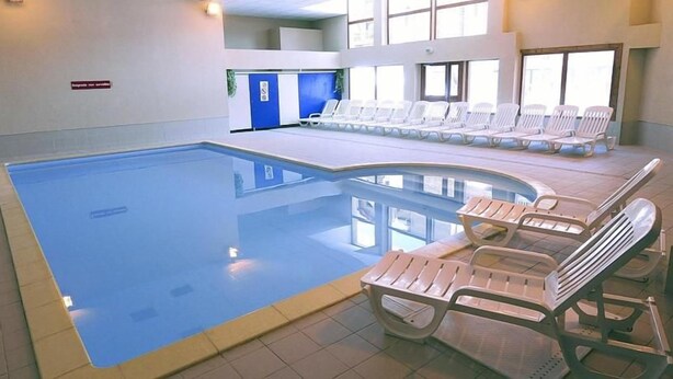 An indoor swimming pool with lounge chairs and a blue-tiled floor. - Residence Goelia Les Flocons D'argent (Aussois)
