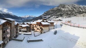 A snow-covered mountain village with chalet-style buildings, a ski lift, and a clear view of the surrounding mountains. - Residence Goelia Les Flocons D'argent (Aussois)