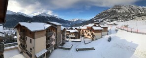A snow-covered mountain village with chalet-style buildings, a ski lift, and a clear view of the surrounding mountains. - Residence Goelia Les Flocons D'argent (Aussois)