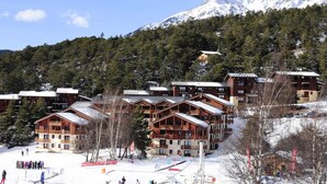 A ski resort with wooden buildings, snow-covered slopes, and a mountain backdrop. - Goelia - Les Balcons D'anaes (Villarodin-Bourget)
