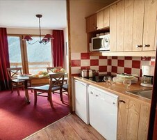Une cuisine compacte dotée de meubles en bois, d’un four à micro-ondes et d’un coin repas avec une table et des chaises.