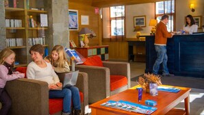 Een hal met een receptiebalie, een bijzettafeltje met tijdschriften, een boekenkast en een zithoek met een laptop.