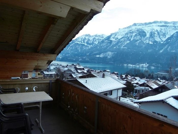 Ein Holzbalkon mit Blick auf schneebedeckte Häuser und Berge.