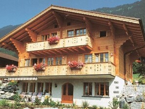 Ein mehrstöckiges Gebäude mit Balkonen, einem Steinfundament und einer Holzfassade.