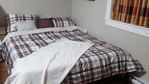 Un dormitorio con cama, un cuadro y una ventana con cortinas.