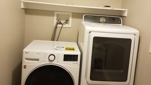 Un cuarto de lavandería con lavadora de carga frontal y secadora apilada.