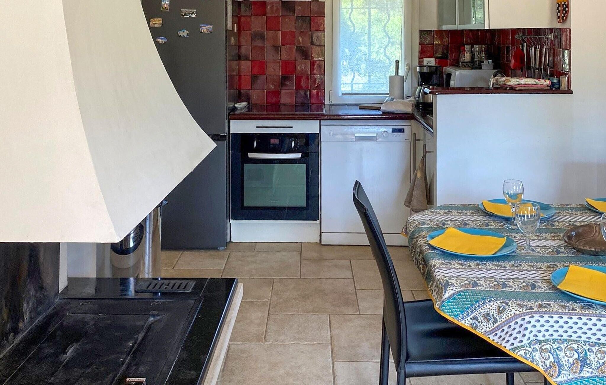 Uma cozinha compacta com lava-louças, forno e área de jantar com mesa posta para dois.