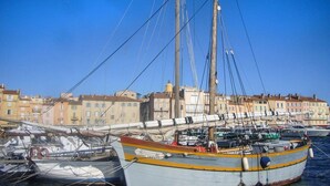 Un port où est amarré un grand voilier, entouré de bâtiments.