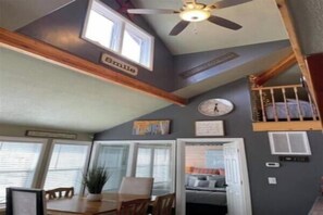 A room with a dining table, chairs, a ceiling fan, a bunk bed, and a window.