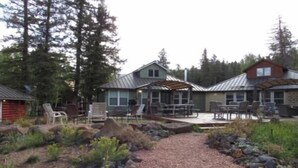 Eine Hütte mit einer Terrasse, Sitzgelegenheiten im Freien und einem Garten.