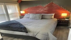Ein Schlafzimmer mit Bett, Nachttischen, Lampen und einem Fenster.