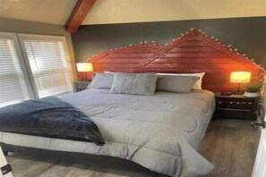 Ein Schlafzimmer mit Bett, Nachttischen, Lampen und einem Fenster.