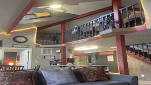 Ein mehrgeschossiges Wohnzimmer mit einer Couch, einem Esstisch und einer Küchenzeile.